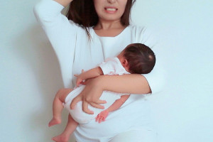 赤ちゃんを抱っこしながら育児にストレスを感じる女性